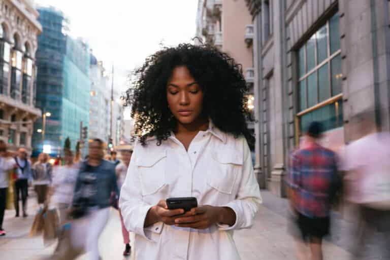 woman texting while walking down a city street during mercury retrograde in astrology forecast by the astrotwins